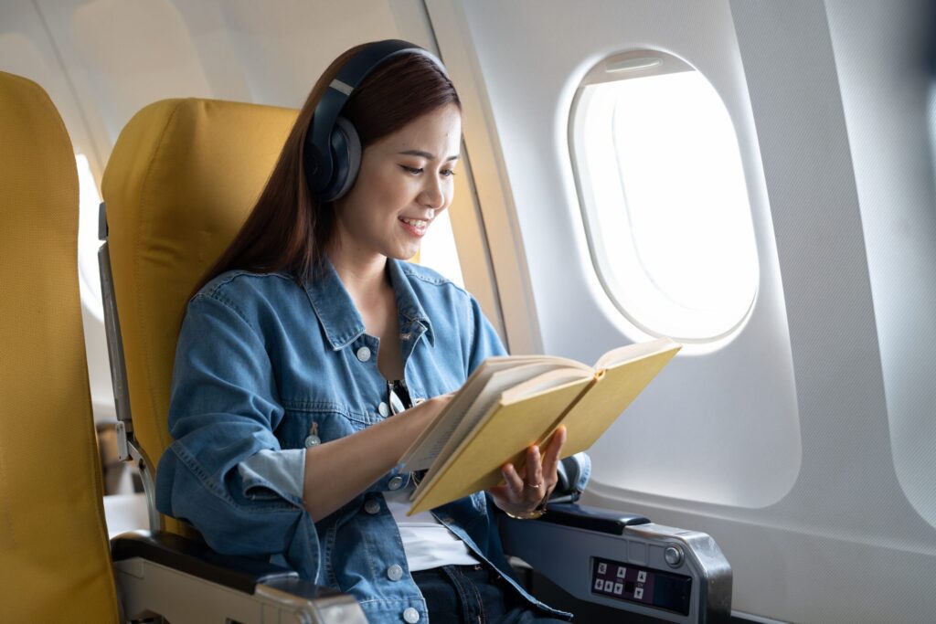 Tips to Stay Comfortable While Travelling | Elect Chauffeurs woman reading on aeroplane