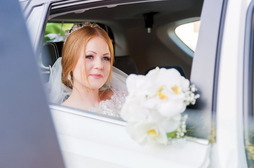 Wedding Car Etiquette | Elect Chauffeurs bride in wedding car holding flowers